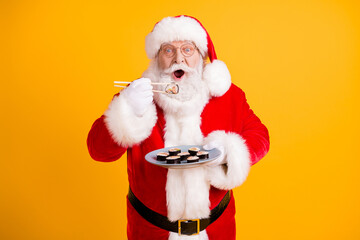 Portrait of his he nice cheerful funny hungry white-haired Santa enjoying eating domestic sushi sashimi roll maki weight loss recipe isolated bright vivid shine vibrant yellow color background