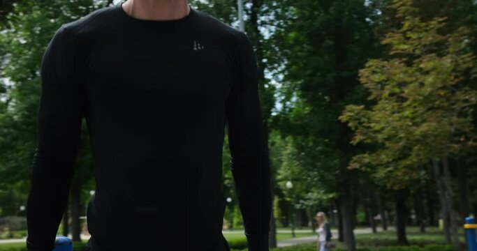 Athletic man doing triceps dip exercise on parallel bars at park