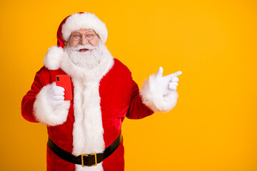 Excited santa claus with big belly use cellphone search x-mas magic fairy christmas eve discount ads point finger copyspace wear cap headwear belt isolated bright shine color background