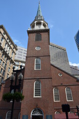 Fototapeta na wymiar The Old South Meeting House in the middle of Boston with streetlamp in the foreground and some skyscrapers in the background with blue sky