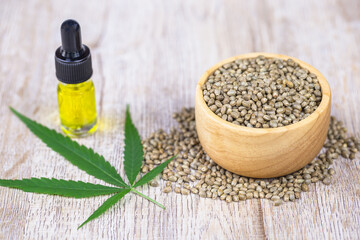 Cannabis seeds in a wooden cup Hemp oil in glass bottles And the hemp leaves on the table The concept of extracting hemp leaves is a natural healing oil, natural herbal medicine.