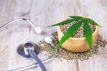 Cannabis seeds in wooden cups and cannabis leaves placed on top. Medical stethoscope The concept of treatment using cannabis as a medical extract.