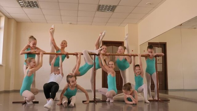 A group of little ballerinas relax in the ballet Studio near the ballet barre after training.