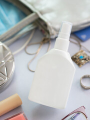 Mockup white bottle of hand sanitizer surrounded with things from woman purse. Vertical shot about health care, hand hygiene and Protection Coronavirus, Covid-19. Lady bag content. Spray anticeptic.
