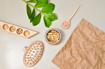 Herb in capsules in wooden bowl on pastel beige background. Beauty products for face and body skin care