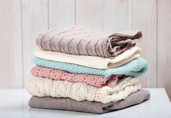 Stack of knitted textured clothing on table.Colorful winter clothes,warm apparel.Heap of knitwear.