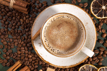 White cup of fragrant coffee on the background of coffee beans, cinnamon