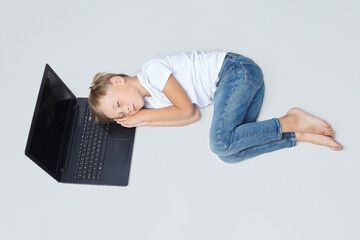 little boy fell asleep on a laptop with his hands folded under his head © Vadzim
