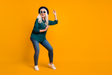 Fototapeta na wymiar Full body photo of crazy granny lady music lover senior party luxury cool look dance youth moves wear green shirt sun specs necklace retro cap shoes isolated yellow color background