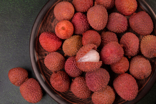 Fresh Lychees on a plate close-up, on a dark green background.