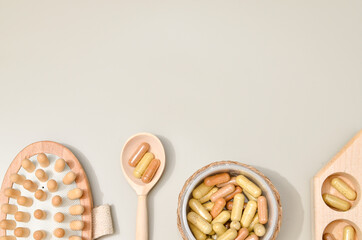 Herb in capsules in wooden bowl on pastel beige background. Beauty products for face and body skin care