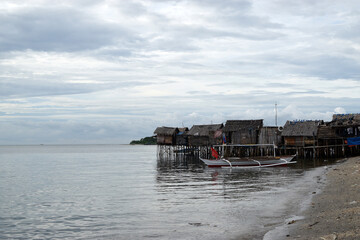Fototapeta na wymiar Small fishing boat anchored beside the over water stilt Bajau shanty houses