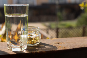 Vitamins for health pills set in a jar and a glass of water in the sun.