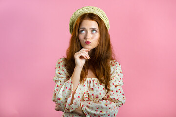 Thinking woman looking up and around on pink background. Happy smiling face expressions. Pretty model with attractive appearance