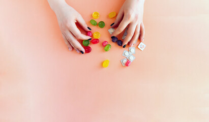 Hands holding candy and pills that are on the table. Choosing a diabetic.
