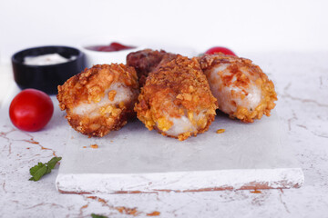 Delicious homemade crispy fried chicken with sauces on white marble background