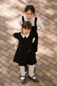 Two girls in school uniform. Two girls in school uniforms stand on the street. View from above
