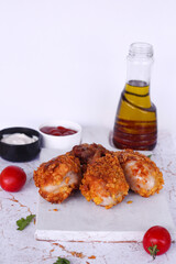 Delicious homemade crispy fried chicken with sauces on white marble background