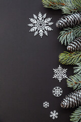 Silver cones and snowflakes, sprigs of blue spruce festive Christmas composition on a black background copy space