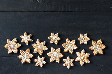 Gingerbread cookies snowflakes decorated with icing on black wooden background. Top view, copyspace