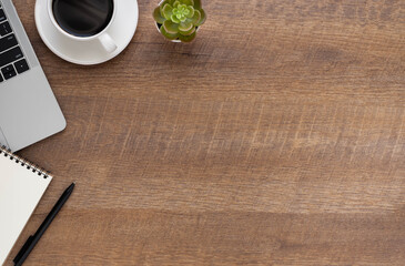 Top view above of Wooden office desk table with keyboard of laptop and notebook, coffee cup with equipment office supplies. Business and finance concept. Workplace, Flat lay with blank copy space.