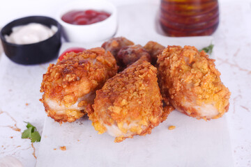Delicious homemade crispy fried chicken with sauces on white marble background