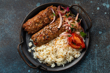 Traditional Turkish dish meat kebab with rice and vegetables in pan on rustic stone background. Middle Eastern meal, from above