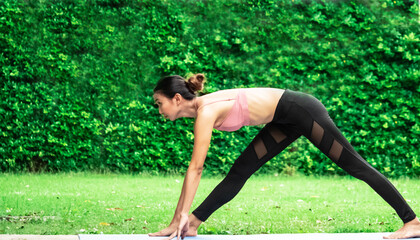 Fototapeta premium Morning outdoor garden grass green park natural holiday female model trainer slim fit sixpack body wear sport bra is playing yoga balance workout fitness class excercise for health care insurance 