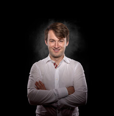 Portrait of a young man in a white shirt on a dark background.