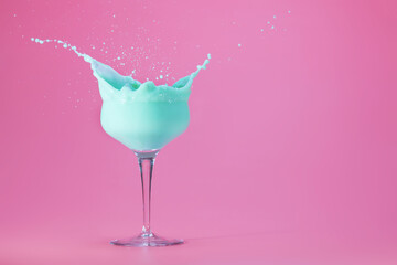 mint creme cocktail splashing on a pastel pink background with space for text