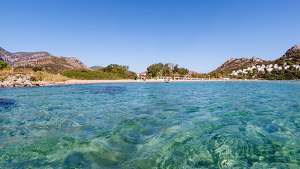 Obraz premium Clear turquoise water of Aegean sea and Caraincir beach. Beautiful Mediterranean seascape of ripple water with sunbeams reflections. Province of Mugla, Datca peninsula, Turkey 
