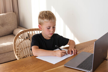 A blond boy draws from an online lesson. Distance learning. Copy space.