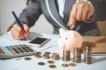 Closeup image businesswoman holding coins putting into piggy bank and calculating. concept saving...