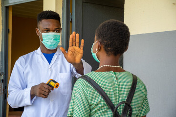 school teacher stops a pupil for body temperature check before entering the classroom
