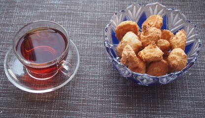 On the table, covered with a brown cloth, is a Cup of tea and a bowl of cookies.