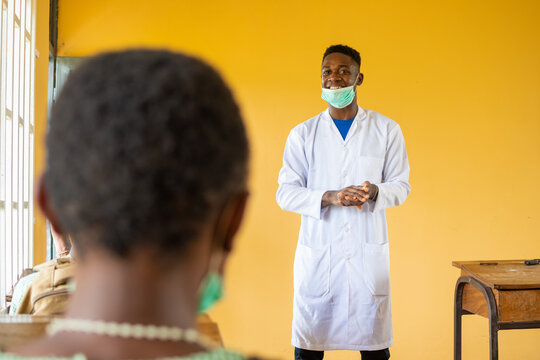 High School Teacher In Africa Wearing Lab Coat And Face Mask In Class Talking To The Class Pupils