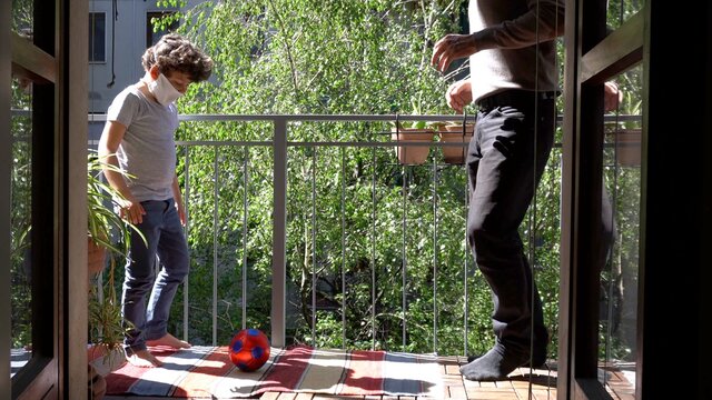 Europe, Italy , Milan - Father and children boy  five years at home during quarantine due n-cov19 Coronavirus outbreak - life stile in apartment - playing soccer football on the balcony
