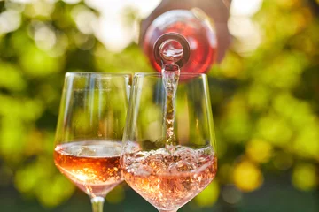 Keuken foto achterwand Pouring rose wine into glasses from a bottle © Rostislav Sedlacek