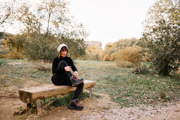 Woman hiker resting on the bench in park after trekking