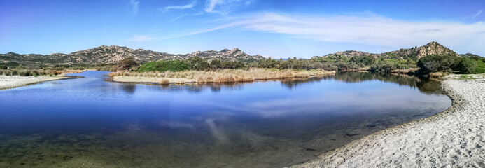 ultra wide panorama of a mountains reflected in a lake in Cala Berchida