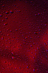 Close up view of cold drops on the glass of beer background. Texture of cooling alcohol drink with macro bubbles on the glass wall. Fizzing or floating up to top of surface. Dark brown colored.
