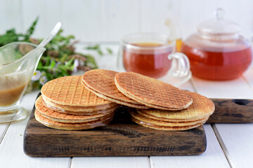 Sweet Breakfast: delicate Dutch waffles with caramel on a wooden Board on a white table