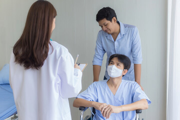 Obraz premium An Asian woman doctor is checking and talking with a man patient about his symptom in hospital. He wears a surgical mask and sits on the wheel chair while another man pushes it.