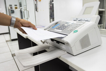 hand man are using a fax machine in the office, equipment for data transmission.