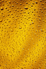 Close up view of cold drops on the glass of beer background. Texture of cooling alcohol drink with macro bubbles on the glass wall. Fizzing or floating up to top of surface. Golden colored.