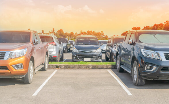 Car parked in asphalt parking lot and one empty space parking  in nature with trees, beautiful cloudy sky and mountain background .Outdoor parking lot with fresh ozone and green environment
