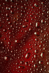 Close up view of cold drops on the glass of beer background. Texture of cooling alcohol drink with macro bubbles on the glass wall. Fizzing or floating up to top of surface. Dark brown colored.