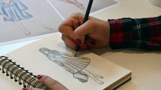 Close up shot of a female hand drawing fashion design sketches