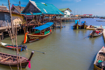 Fototapeta na wymiar Traditional boats moored by the settlement built on stilts of Ko Panyi in Phang Nga Bay, Thailand