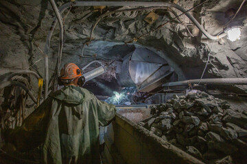 Man miner loading gold ore in minecarts wagons